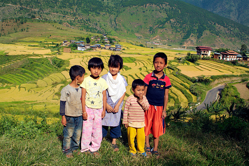 Punakha, Bhutan - September 23rd 2007: Group of unidentified children and tiny village with rice fields in Punakha valley