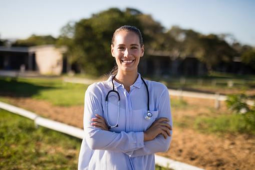 Portrait of smiling female vet with arms crossed standing at barn