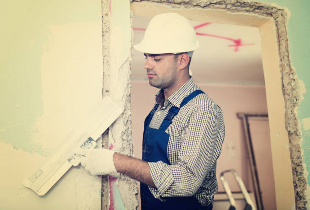 istock Repairman in helmet plastering wall with putty 838082900