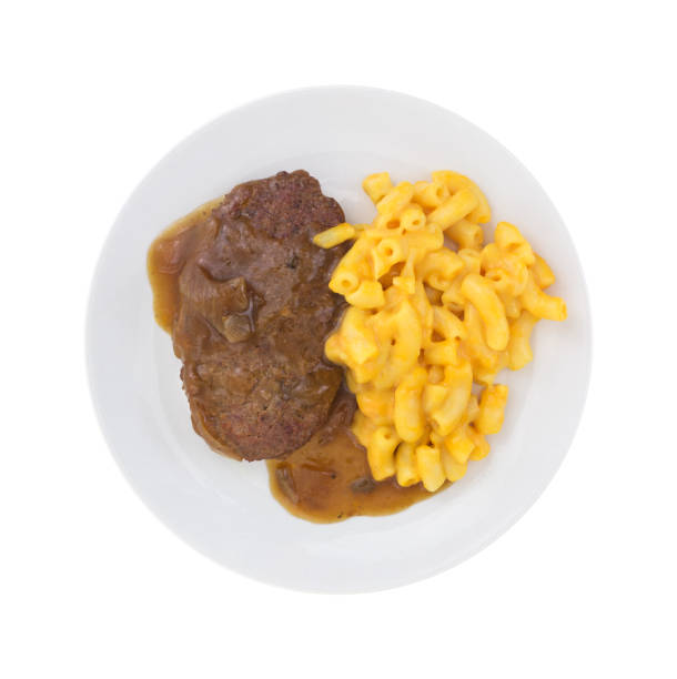 Salisbury steak meal on a plate Top view of a meal of salisbury steak with gravy macaroni and cheese on a plate isolated on a white background. salisbury steak stock pictures, royalty-free photos & images