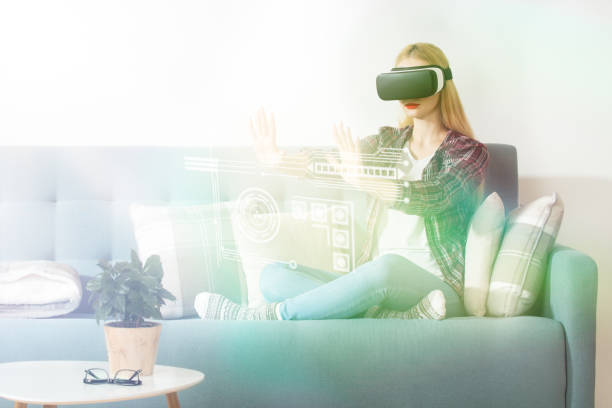 Attractive woman wearing virtual reality glasses sitting on a couch.