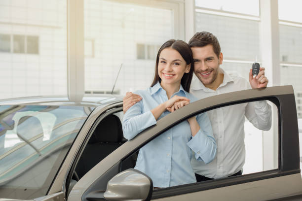 Young People in a Car Rental Service Transportation Concept Young man and woman in a car rental service standing hugging reduction looking at camera finance business stock pictures, royalty-free photos & images