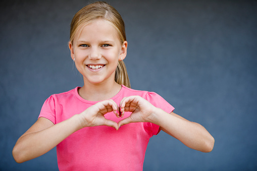 Cute smiling girl making heart sign