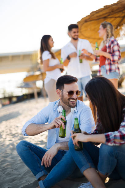 istock Happy couple smiling and drinking beer at beach 838099390