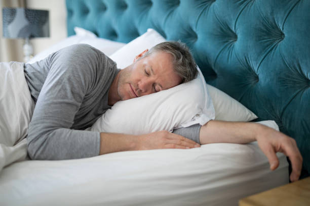 Man sleeping on bed in bedroom Man sleeping on bed in bedroom at home wavebreakmedia stock pictures, royalty-free photos & images