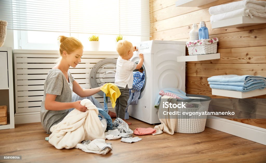 Happy family mother   housewife and children in   laundry load washing machine Happy family mother  housewife and children in the laundry load a washing machine Laundry Stock Photo
