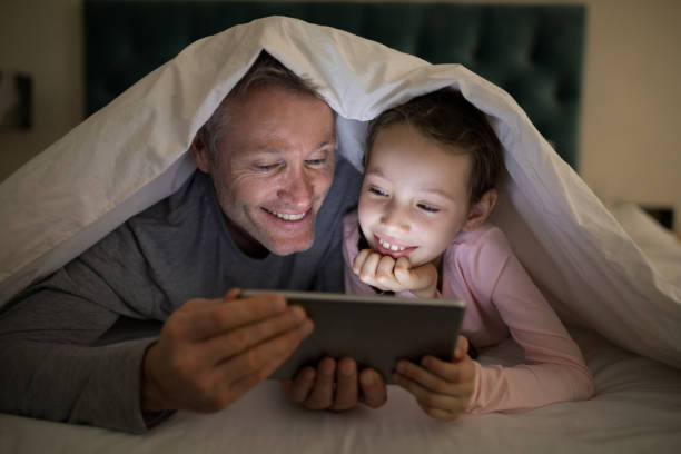 istock Father and daughter using digital tablet under blanket on bed 838108388