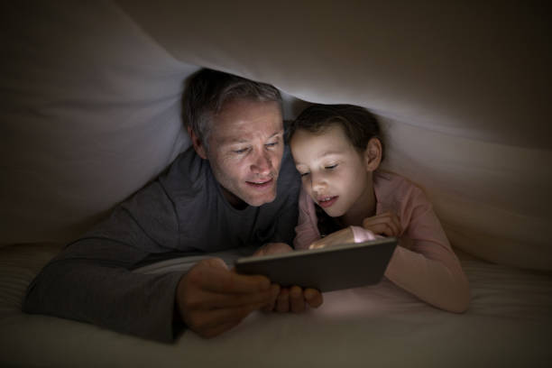 istock Father and daughter using digital tablet under blanket on bed 838109782