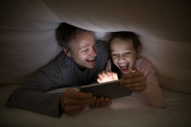 istock Father and daughter using digital tablet under blanket on bed 838109822