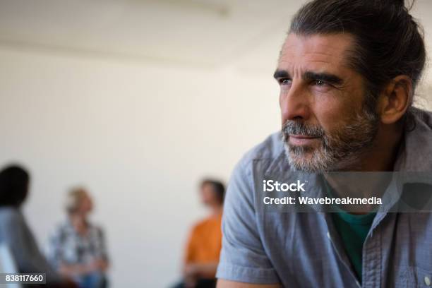 Close Up Tensed Man With Friends Discussing In Background Stock Photo - Download Image Now