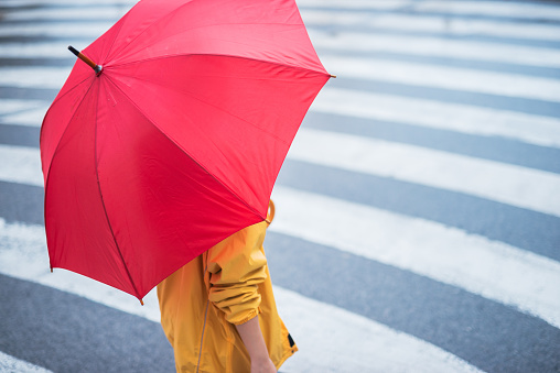 Woman with umbrella crossing the pedestrian. Selective focus on the hand.