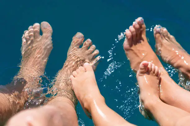 Photo of Happy family. Bare feets in the water of the sea boy, mother, father. Positive human emotions, feelings, joy. Funny cute child making vacations and enjoying summer.