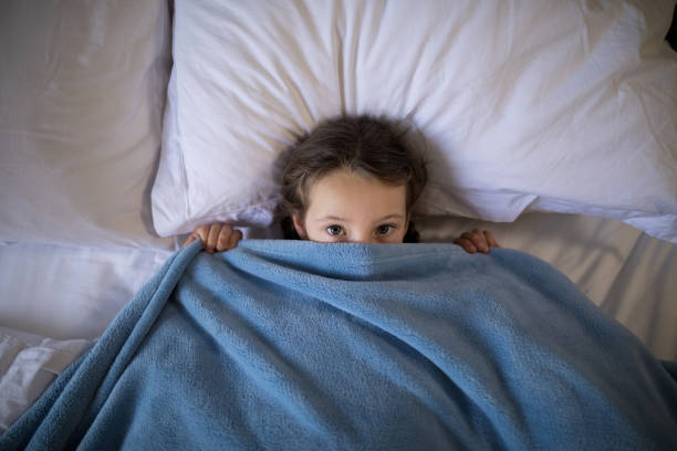 istock Girl covering her face under the blanket while lying on bed 838162896