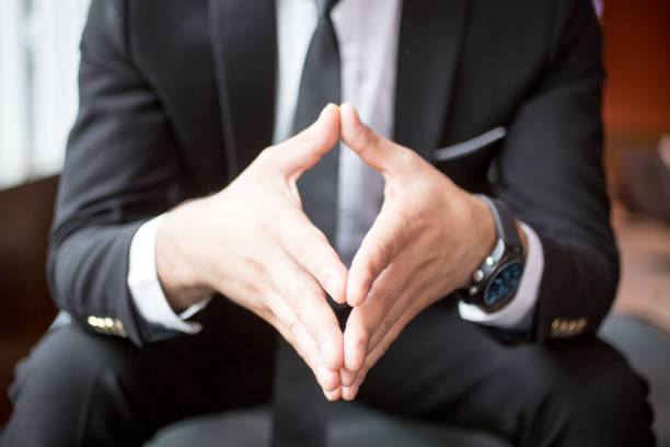 Cropped view of adult business man sitting and holding hands together. Front view.