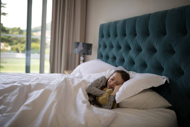istock Girl sleeping on bed with teddy bear in bedroom 838164354
