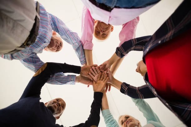 istock Directly below shot of happy senior friends stacking hands 838169468