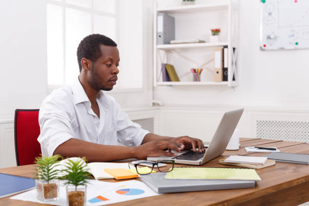 istock Young black businessman working with laptop in modern white office 838189656