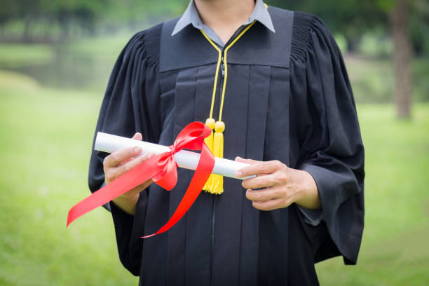 istock Graduate in gown holding certificated in hand 838190198