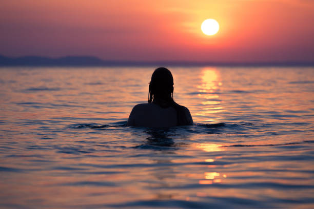 istock Female in ocean at sunset 838195196