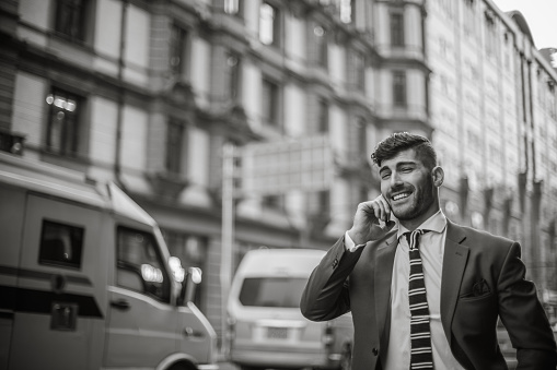 Black and white young businessman using cell phone in city