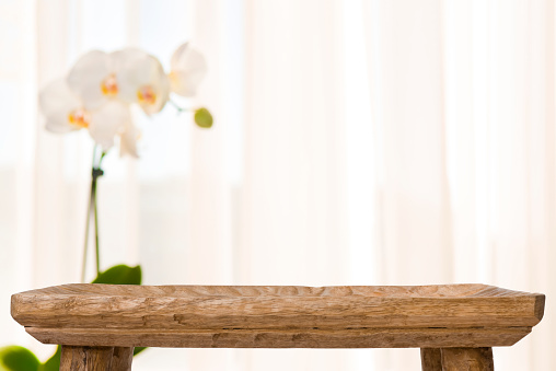 Wooden bathroom table on abstract blurred background with orchid flower