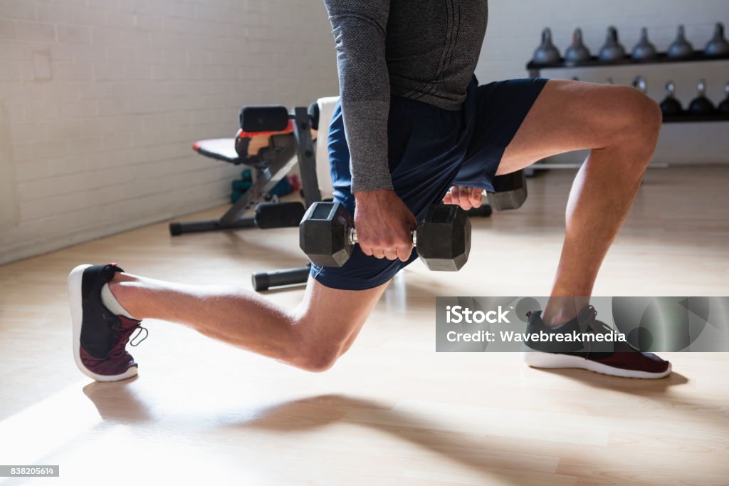 Low section of male athlete exercising lunges in club Low section of male athlete exercising lunges in fitness club Lunge Stock Photo