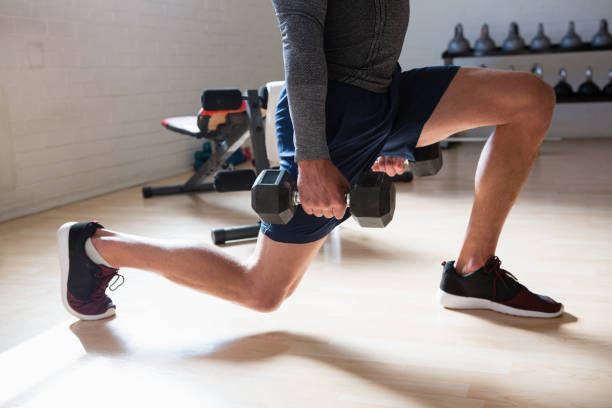Low section of male athlete exercising lunges in club stock photo