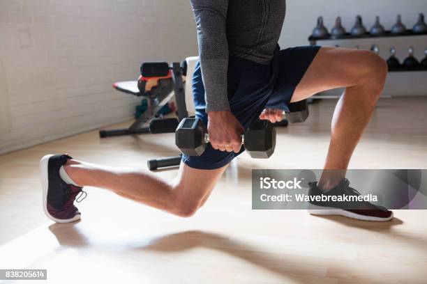 Low Section Of Male Athlete Exercising Lunges In Club Stock Photo - Download Image Now