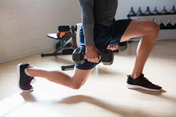 Photo of Low section of male athlete exercising lunges in club