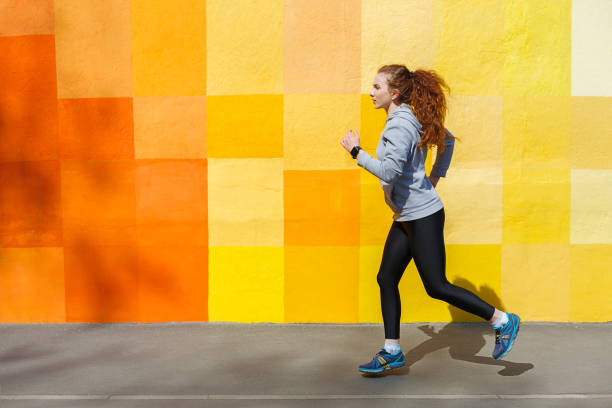 istock Side view of woman running against bright wall 838205806