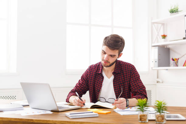istock Young concentrated businessman takes notes in modern white office 838229826