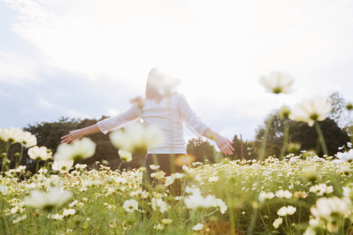 a woman walking on the flower field with spreading her hands out 