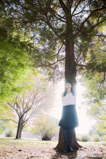 a woman standing in front of the tree and looking up