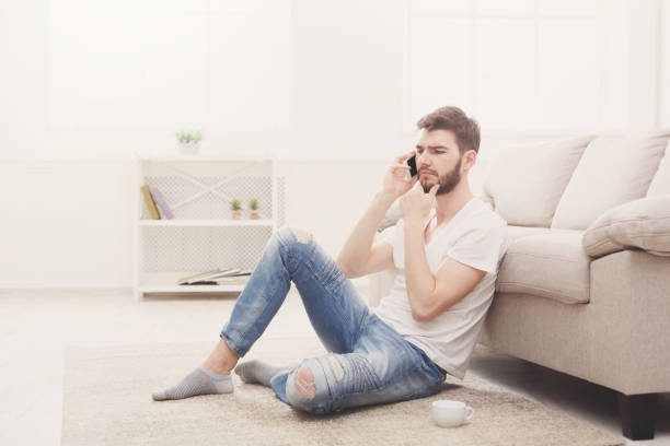 istock Pensive young man at home talking on mobile 838233130