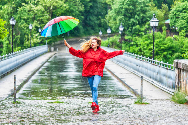 belle fille avec parapluie danser sous la pluie - child little girls smiling autumn photos et images de collection