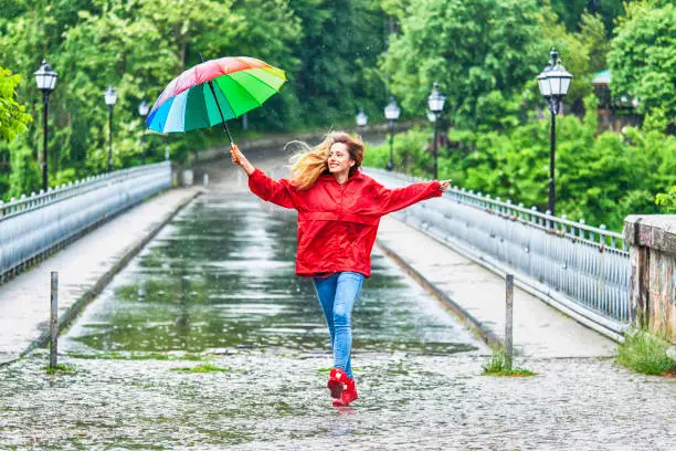 Photo of Beautiful girl with umbrella dancing in the rain