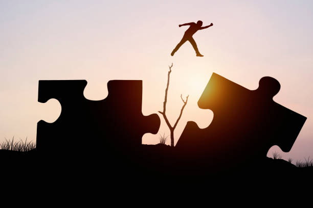 istock silhouette man jumping on jigsaw, concept as can be cross problem and barrier to success in business and finance 838237258
