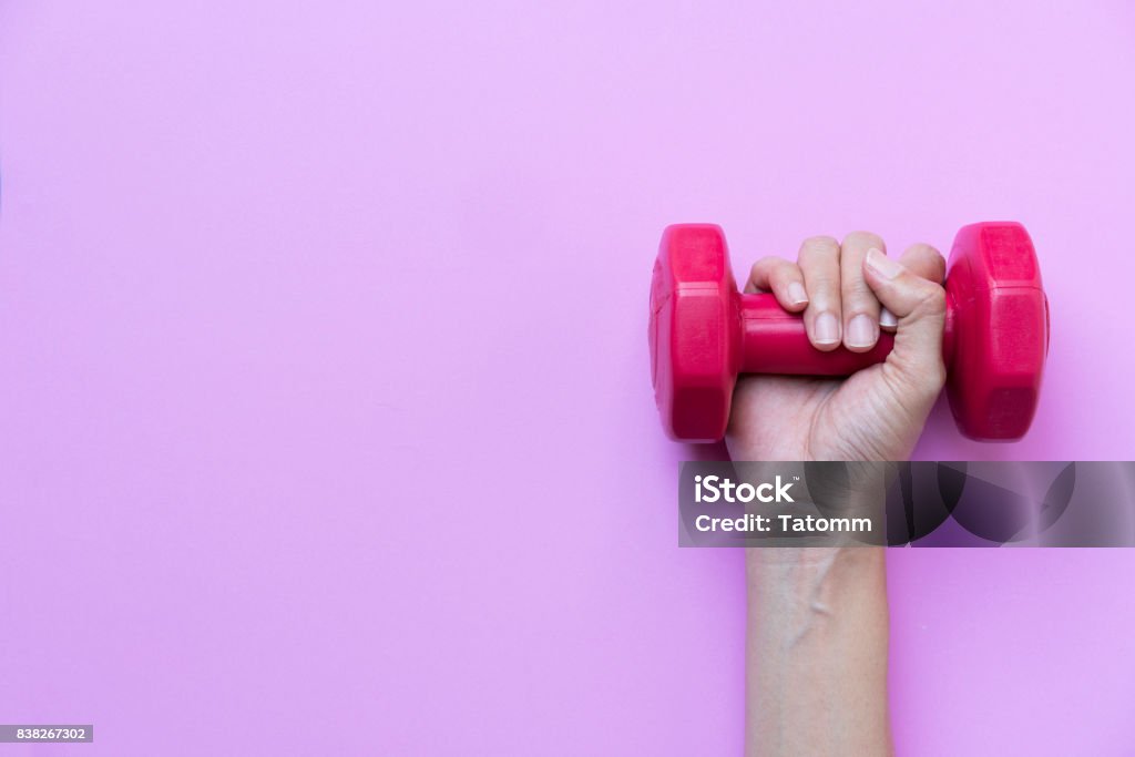 woman hand holding red dumbbell on pink background Dumbbell Stock Photo