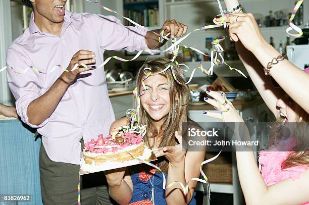 Friends Throwing Streamers Over Woman Holding Cake Stock Photo - Download Image Now - Birthday, Party - Social Event, Friendship