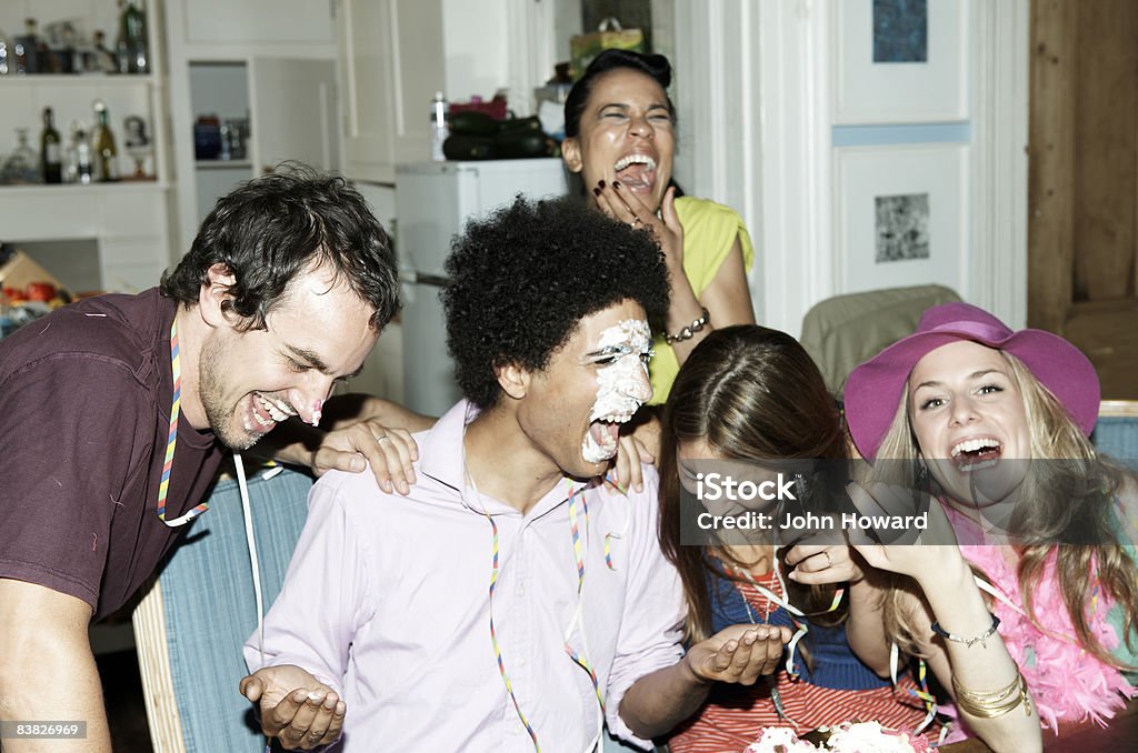 Man with icing on his face laughing with friends  Party - Social Event Stock Photo