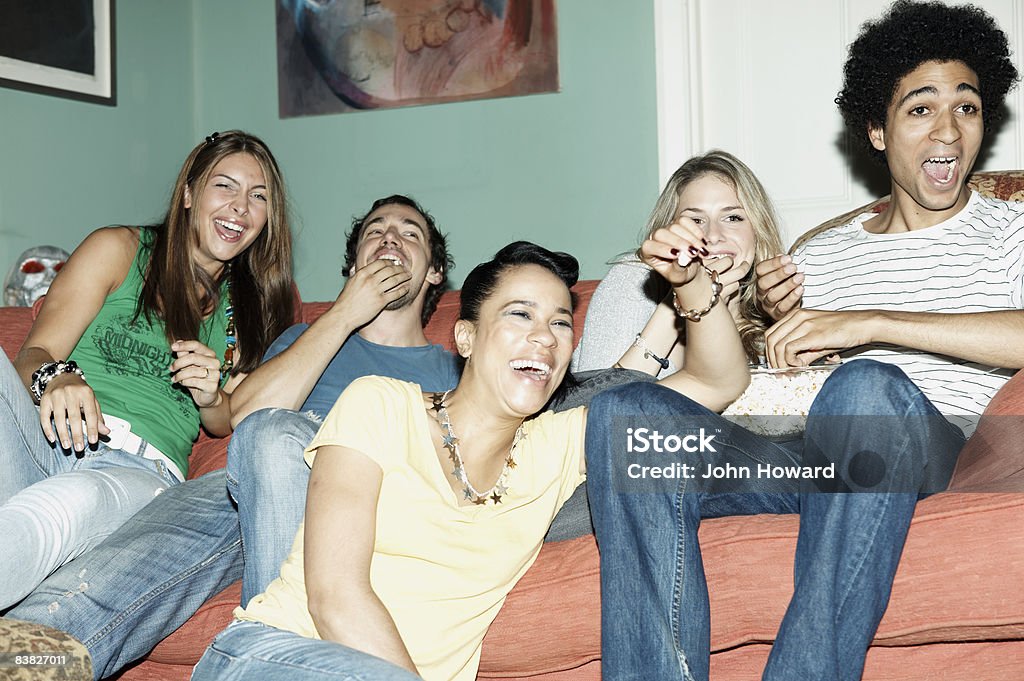 Friends laughing watching TV together  Watching TV Stock Photo