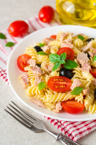 istock Fusilli pasta salad with tuna, tomatoes, black olives and basil on gray stone background 838276578