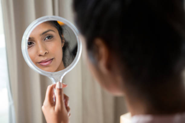 woman reflecting on hand mirror - mirror imagens e fotografias de stock