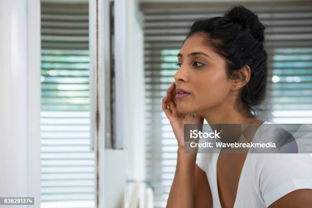 Woman Touching Face In Bathroom Stock Photo - Download Image Now - Acne, Indian Ethnicity, One Woman Only