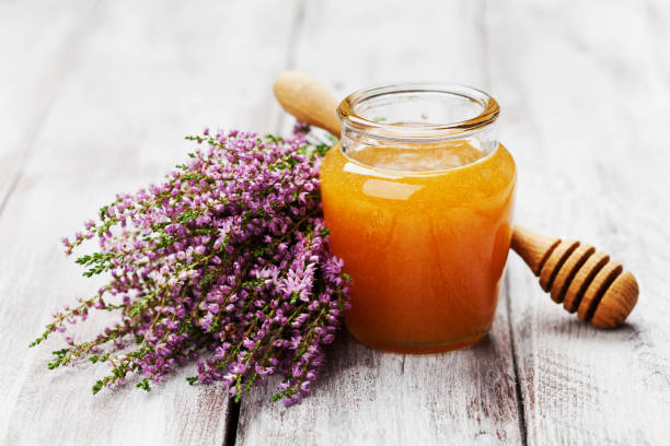 Delicious fresh honey in pot or jar and flowers heather on wooden vintage background. stock photo