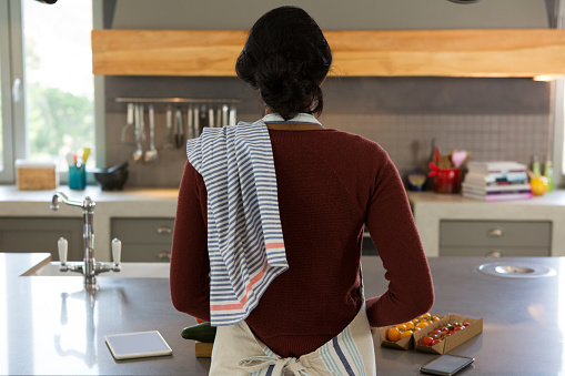 Rear view of woman cooking food in kitchen at home