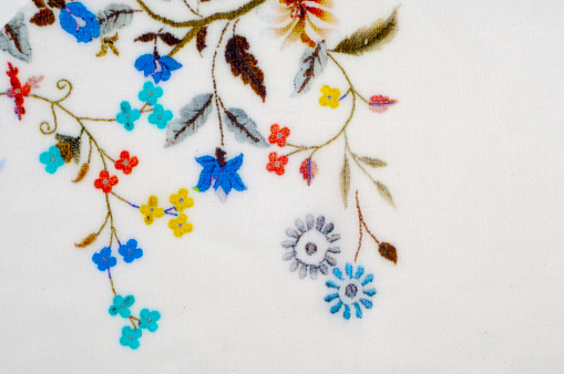 texture, background, fabric cotton white. With flowers stylized embroidery. a soft white fibrous substance that surrounds the seeds of a tropical and subtropical plant