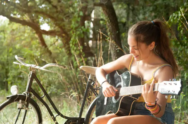 Photo of Teenager playing acoustic guitar in the countryside