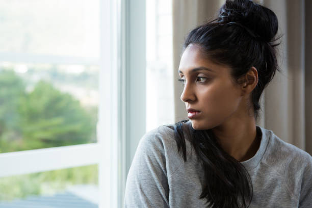 istock Thoughtful young woman by window 838336448