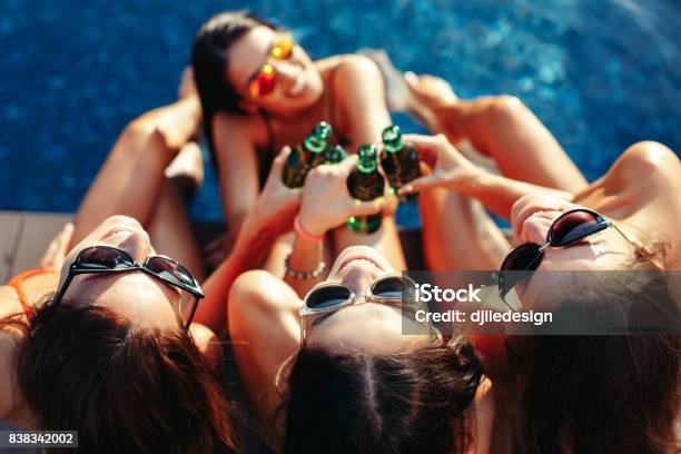 Four Young Women Toast With A Beer In The Pool And Smiling Stock Photo - Download Image Now